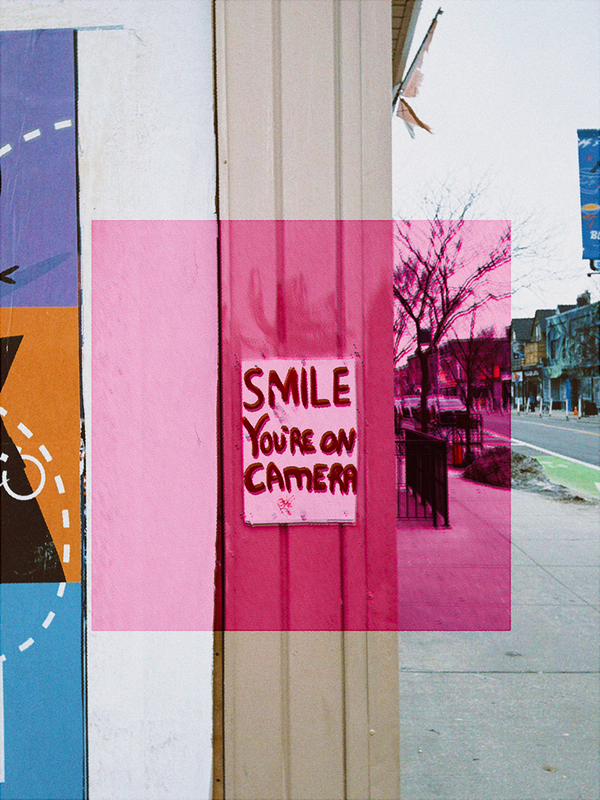 a photo of a sign that says smile you're on camera on a building. there's a pink square overlayed at the centre of the frame. 